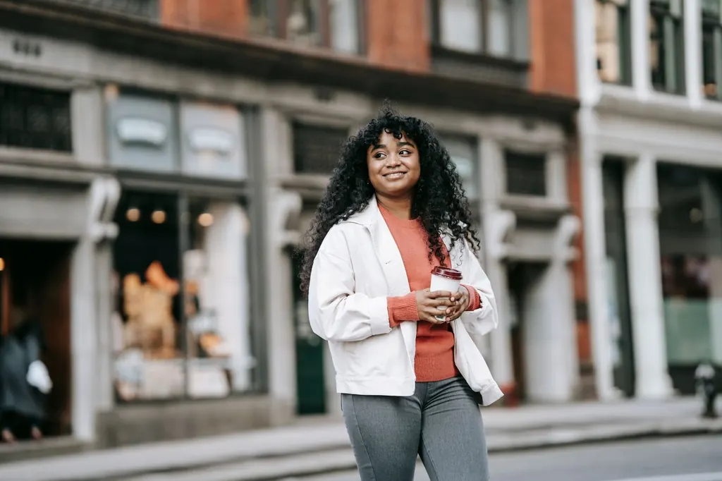 Smiling woman with a coffee walking down a city street