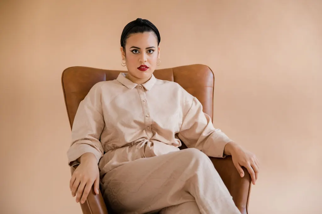 Confident woman in a linen outfit seated in a leather armchair