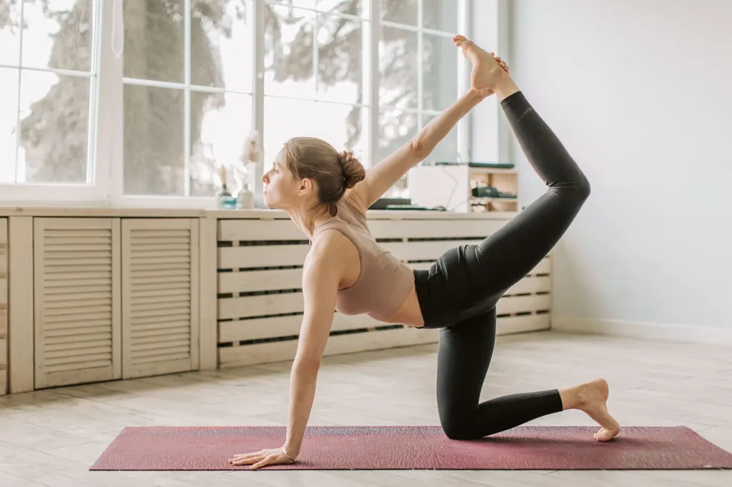 Woman doing a balancing yoga stretch in a bright room