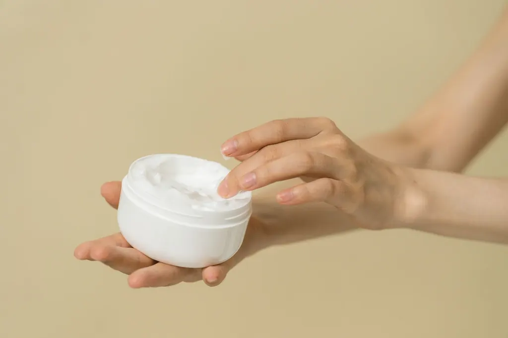 Hands applying a healing cream from a jar