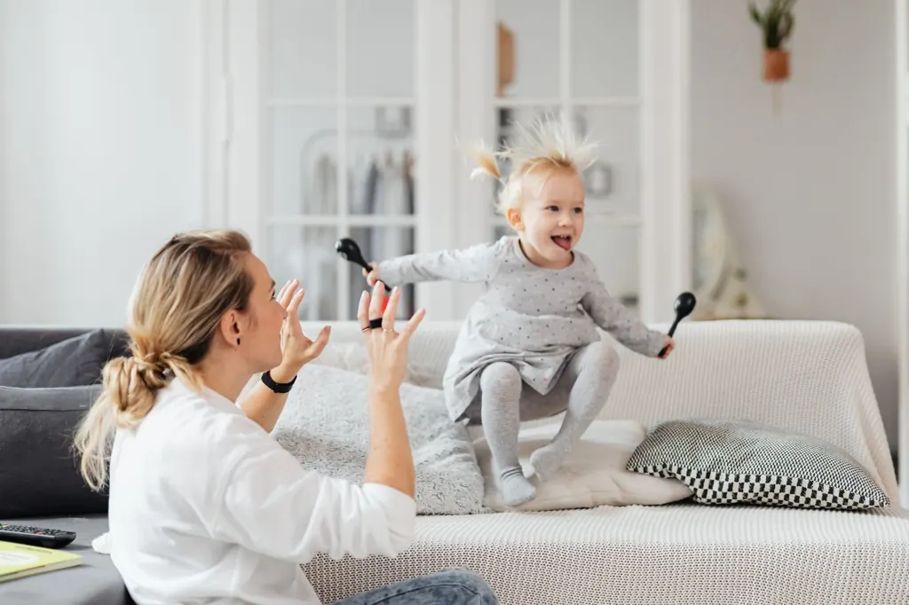 Mother laughing and playing with her toddler on the sofa